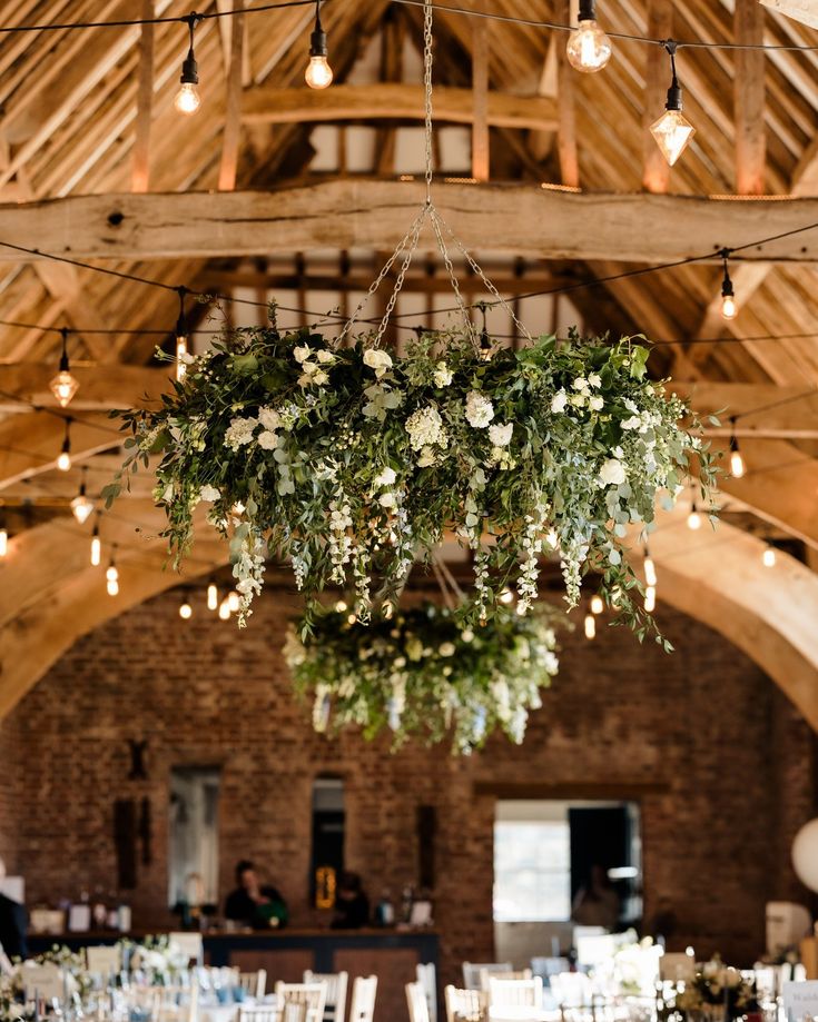 the chandelier is filled with flowers and greenery for an elegant wedding reception