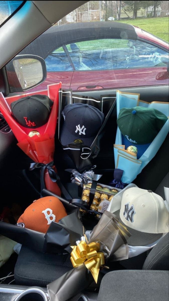 baseball hats and other items are in the back seat of a car with a gold bow