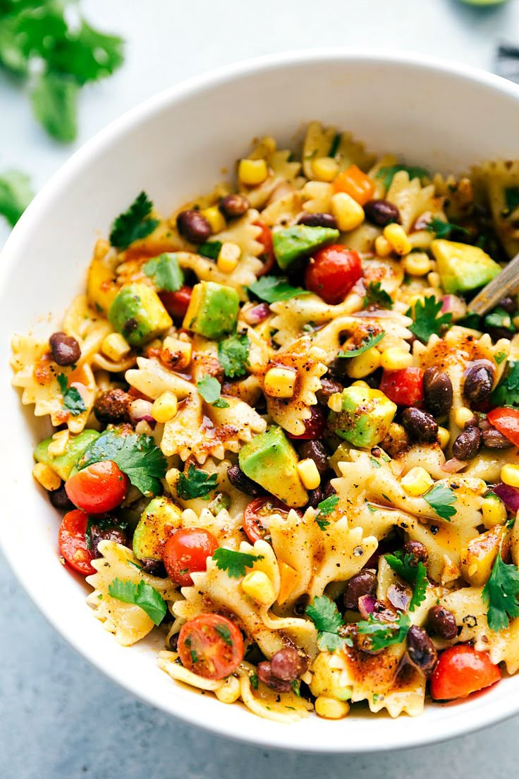 a white bowl filled with pasta salad and garnished with fresh cilantro