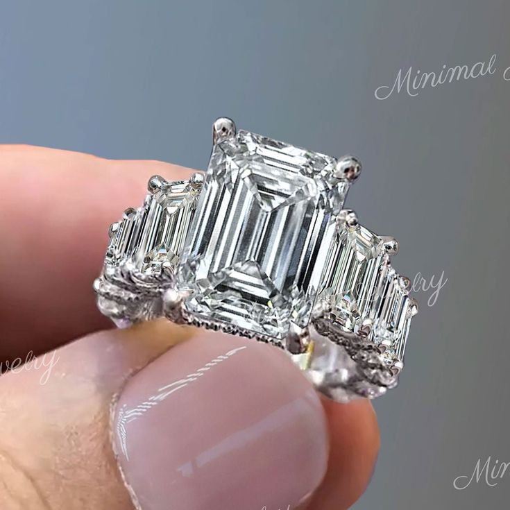 someone is holding an emerald cut diamond ring