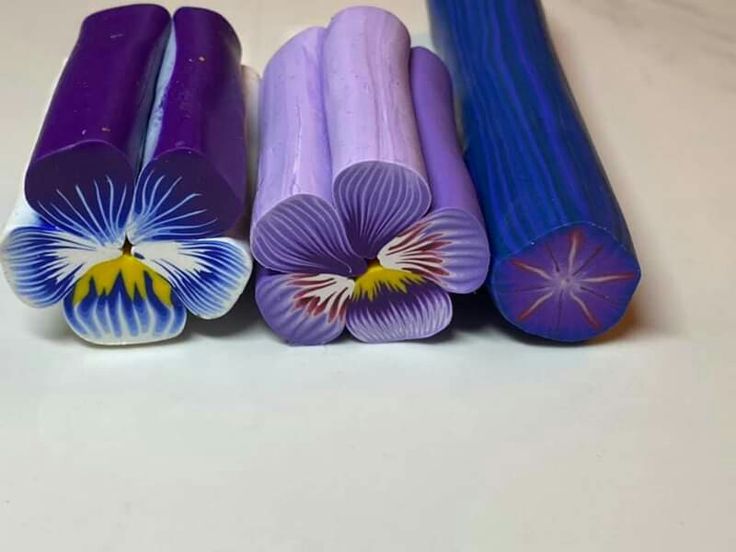 four different colored pencils sitting next to each other on a white counter top with flowers painted on them