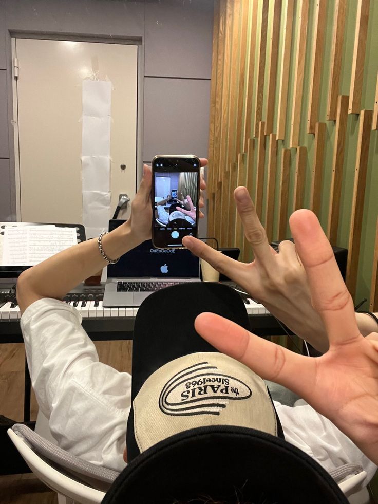 two people are taking pictures with their cell phones in front of a keyboard and piano