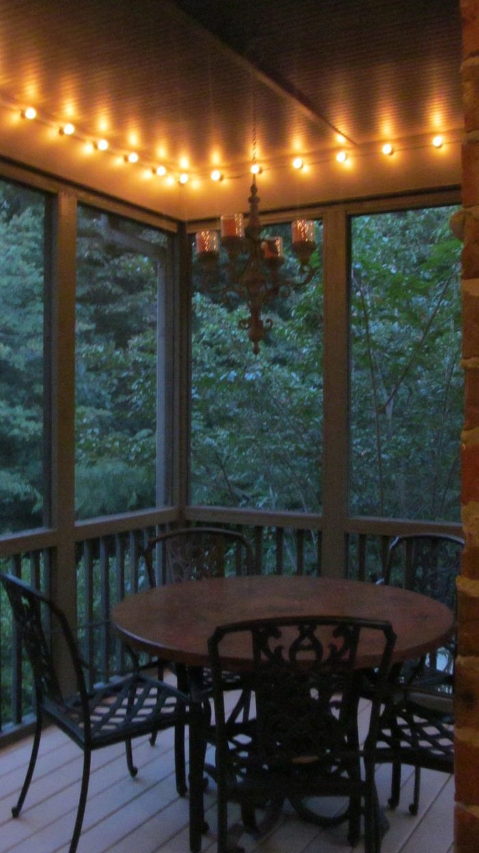 an outdoor dining area with lights strung from the ceiling and patio furniture on the deck