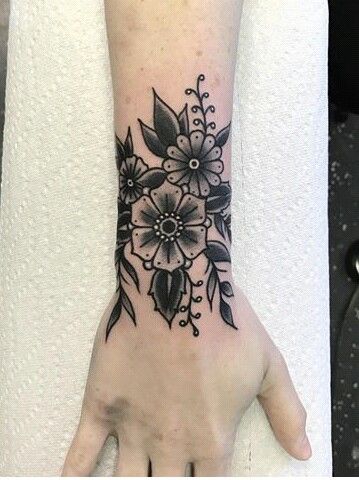 a woman's hand with a black and white flower tattoo on the left wrist