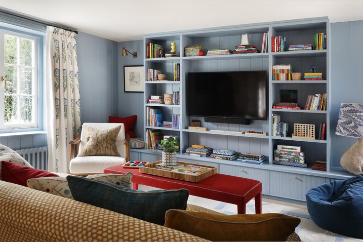 a living room filled with furniture and a flat screen tv mounted on a blue wall