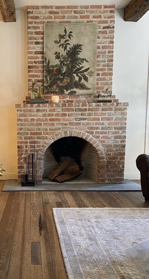 a living room with a fire place and rugs in front of the brick fireplace