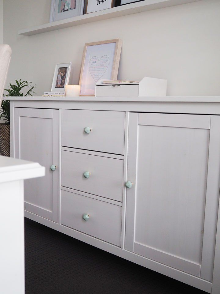 a white dresser with drawers and pictures on top