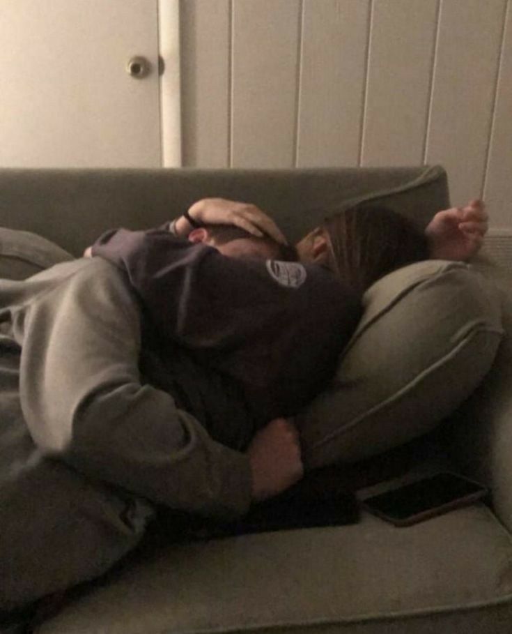 a man laying on top of a couch with his head in the pillow while covering his face