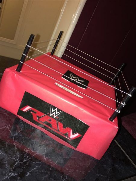 a red wrestling cage sitting on top of a black table next to a wall and door