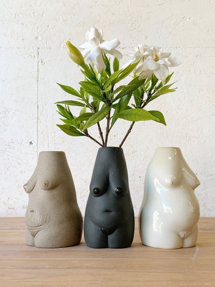 three ceramic animal vases sitting on a table with flowers in them and one is holding a plant