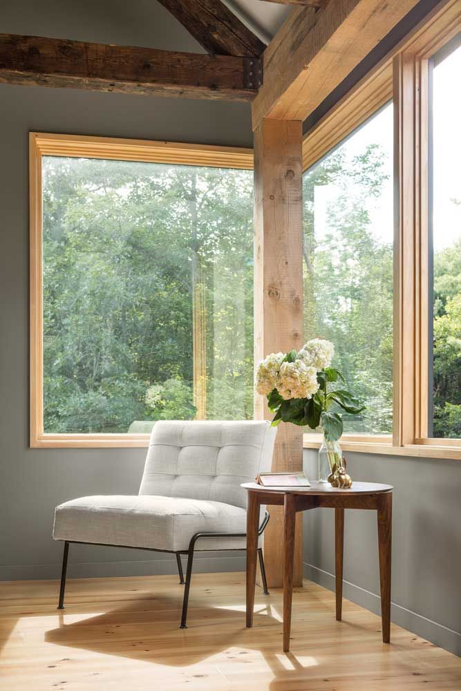 a white chair sitting in front of a window next to a table with flowers on it