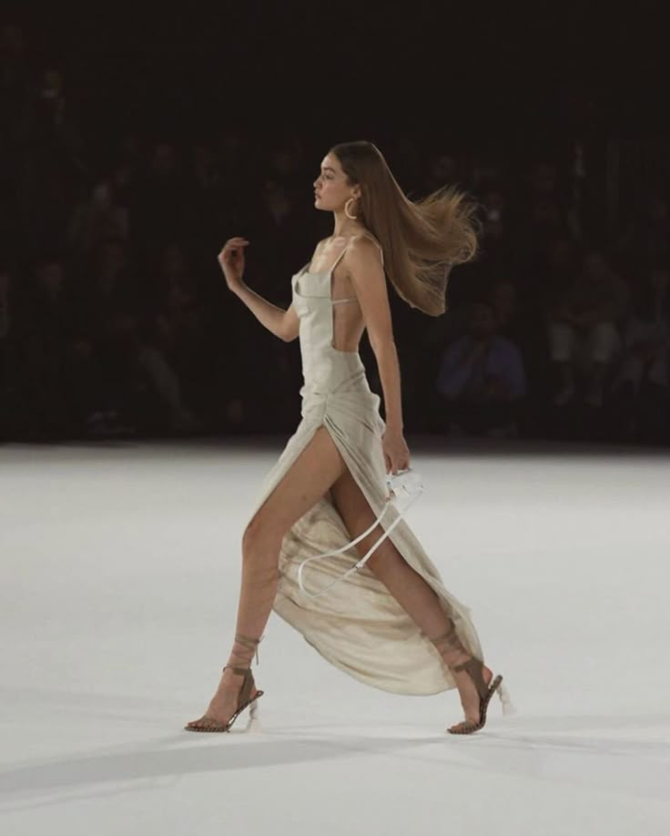 a woman walking down a runway in a white dress