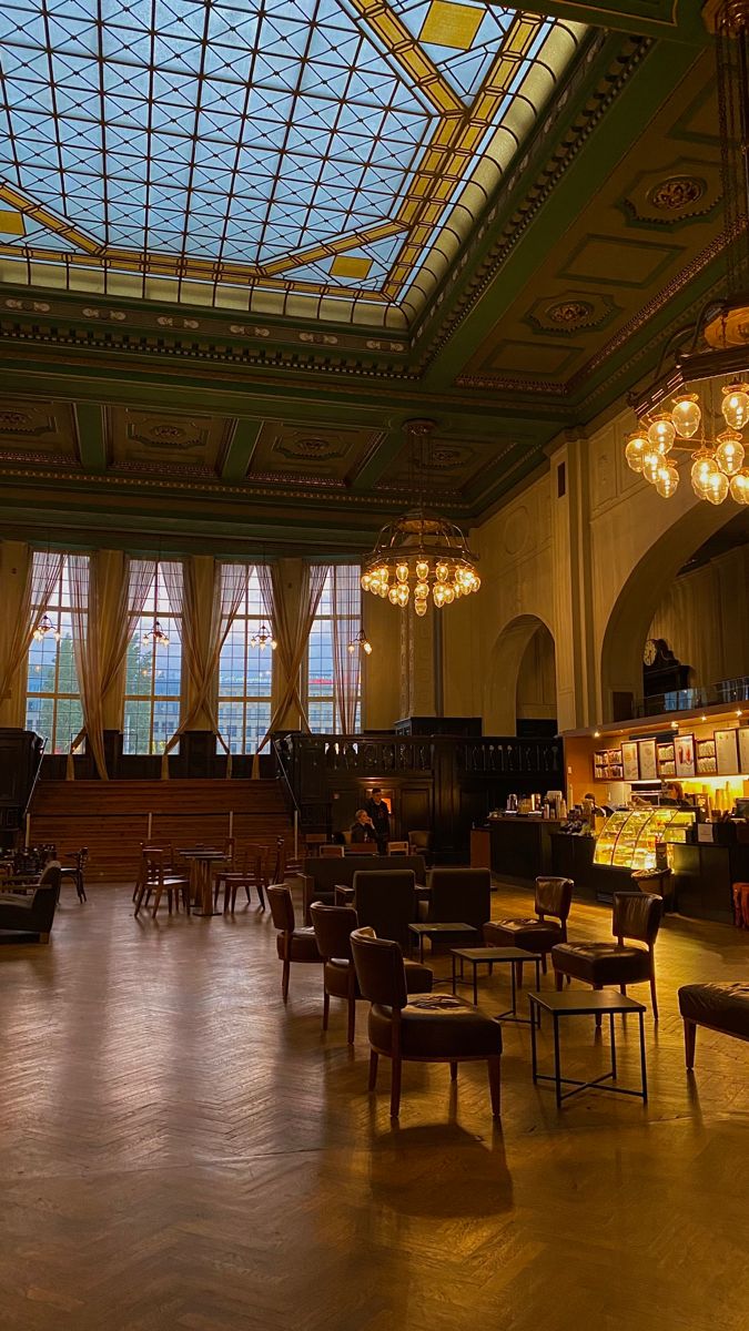 a large room filled with lots of chairs and tables under a glass ceiling covered in lights