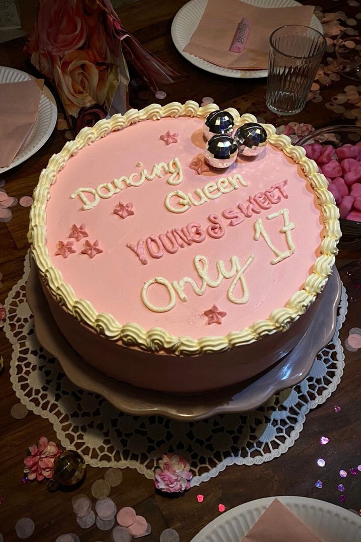 a birthday cake with pink frosting and writing on the top is surrounded by confetti