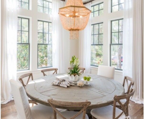 the dining room table is set with white chairs and a chandelier above it