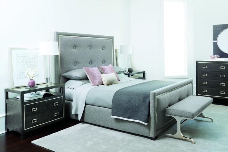 a bedroom with a bed, night stand and dressers in grey color scheme on hardwood flooring