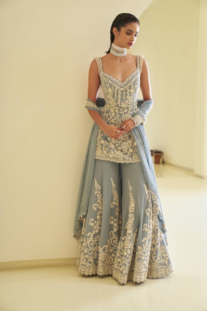 This georgette sharara set features all-over thread, pearl, and crystal embroidery. The ensemble has cutwork embroidery at the hem of the sharara top and graded pearl details at the shoulder. The back of the top has pearl strings. It is paired with a matching four-sided embroidered dupatta.From Seema Gujral's Fiori collection. DELIVERY TIMEPlease allow 8-12 weeks for your outfit to arrive. FABRIC DETAILSGeorgette Professional cleaning only. Sharara Top, Cut Work Embroidery, Indian Outfits Modern, Pearl Strings, Georgette Sharara, Trendy Outfits Indian, Indian Outfits Lehenga, Lehenga Designs Simple, Crystal Embroidery