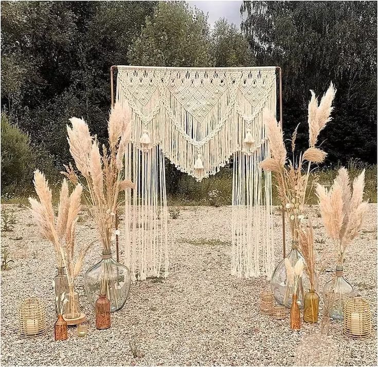 an outdoor area with vases filled with flowers and bottles in front of a string curtain