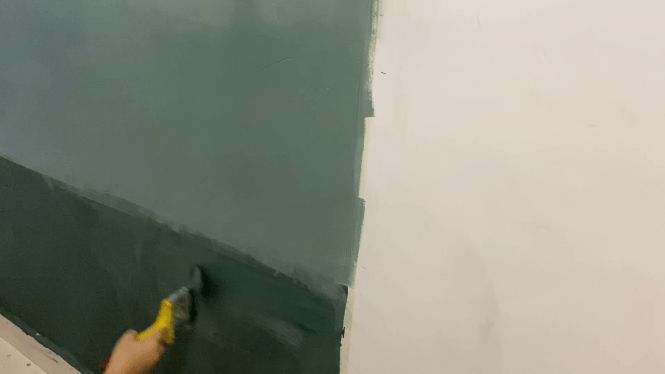 someone is painting the wall with green paint