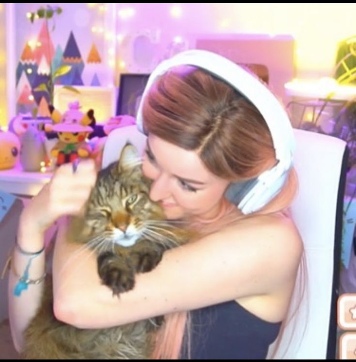 a woman holding a cat in her arms and listening to music on the headphones