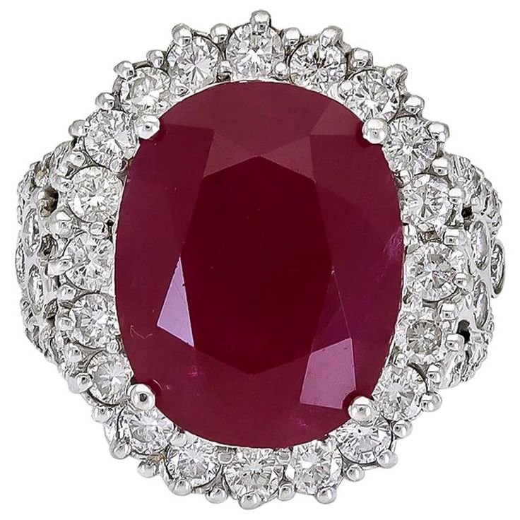 an oval shaped ruby and diamond ring in white gold with diamonds around the center stone