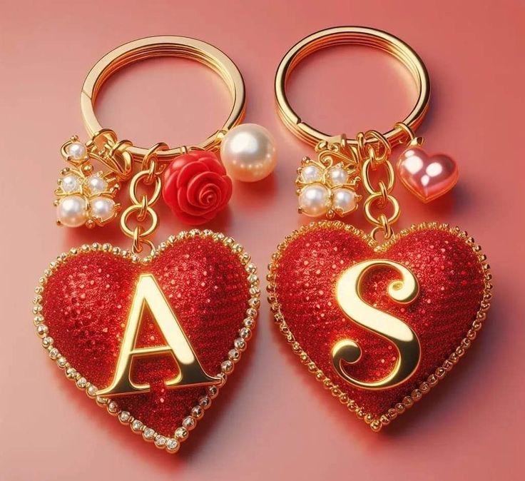 two red heart shaped key chains with initials and pearls on them, sitting next to each other