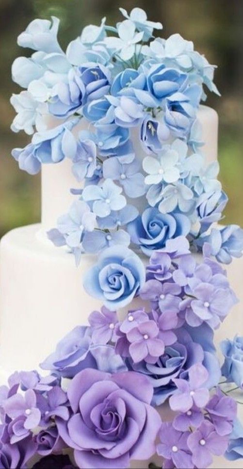 a three tiered white cake with blue flowers on top