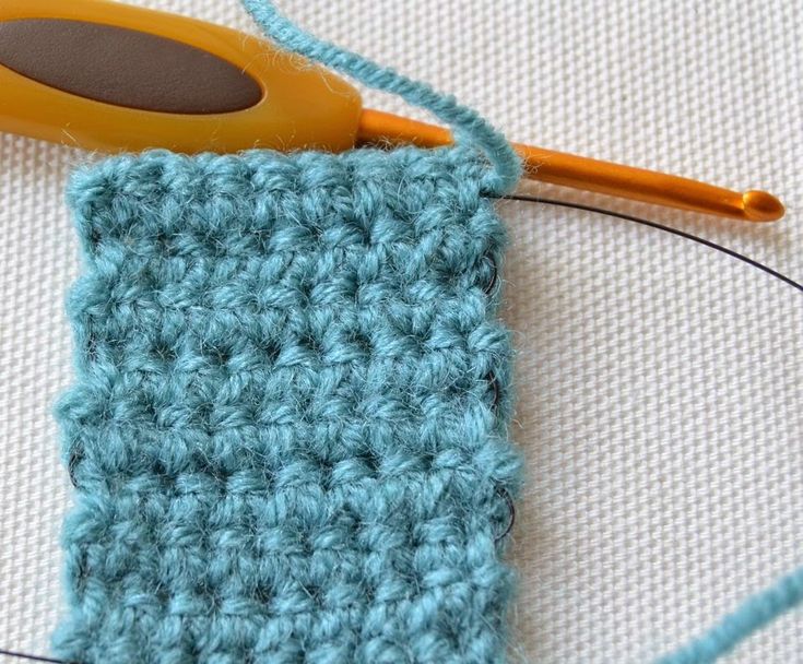 the crochet stitch is being worked on by a pair of yellow handled scissors