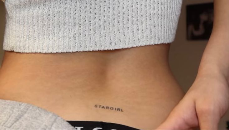 a woman's lower back with the word tattoo on her left ribcage