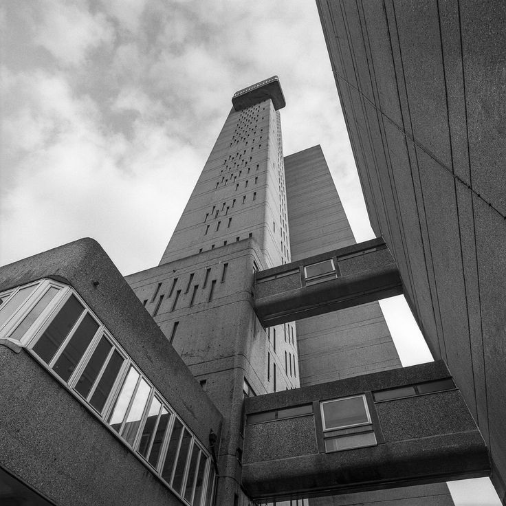 an upward view of a tall building with windows on the top and bottom floors in black and white