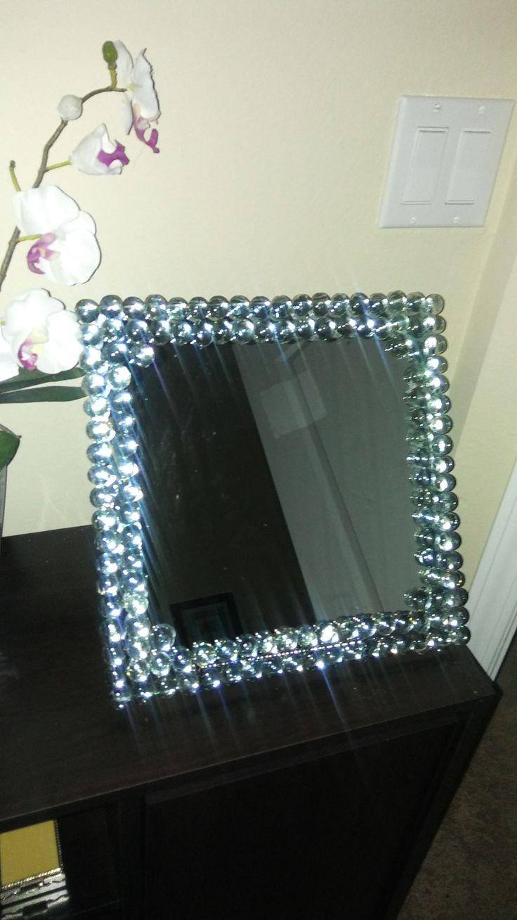 a mirror sitting on top of a dresser next to a vase with flowers in it