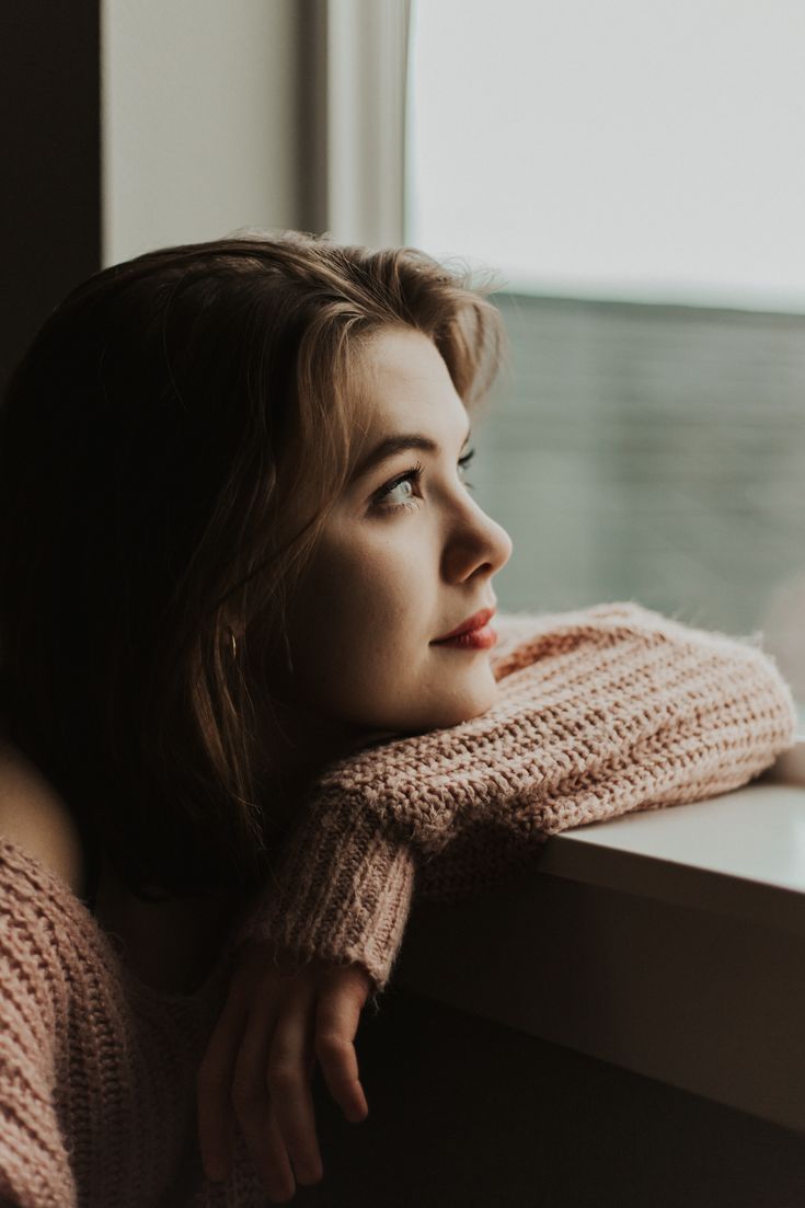 a woman leaning on a window sill looking out the window