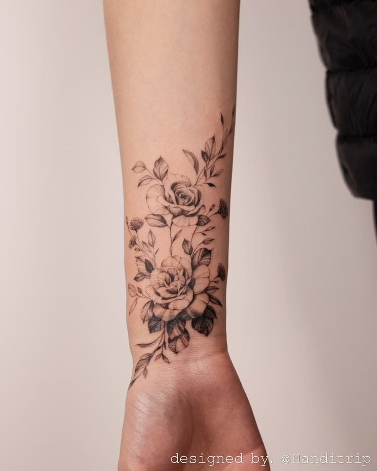 a woman's arm with a flower tattoo on her left wrist and the other hand