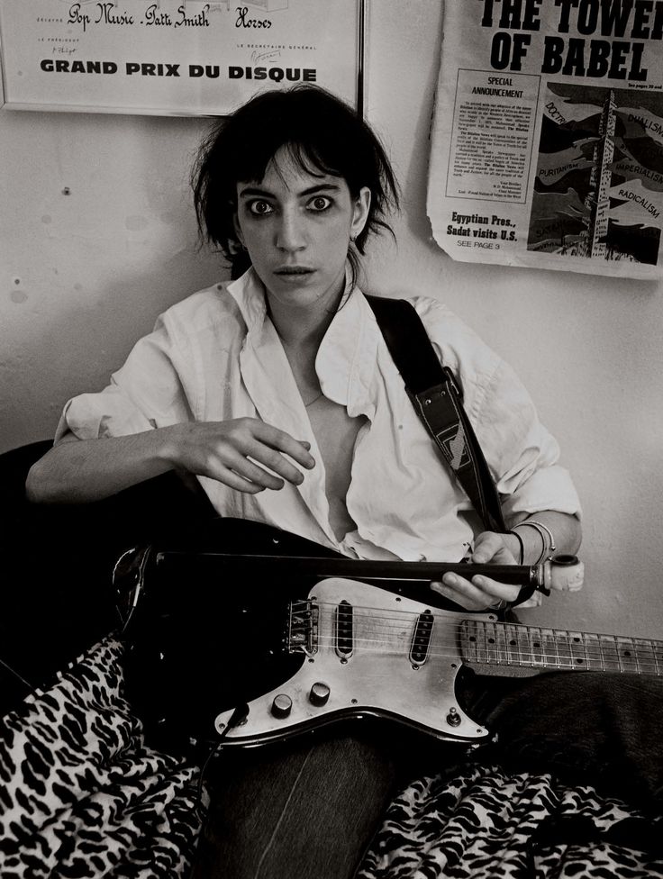 a woman sitting on top of a bed holding an electric guitar in front of her face