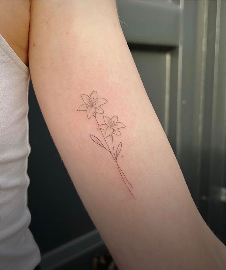 a woman's arm with a single flower tattoo on the left side of her arm