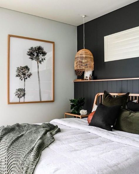 black and white bedroom with palm trees on the wall, bed linens and pillows