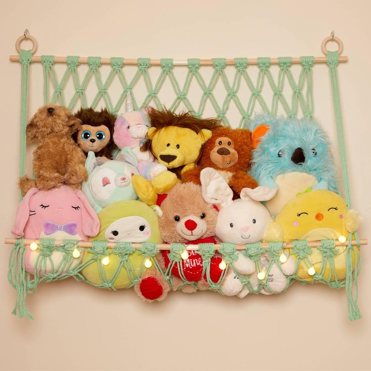 a bunch of stuffed animals sitting on a shelf with lights in the corner behind them