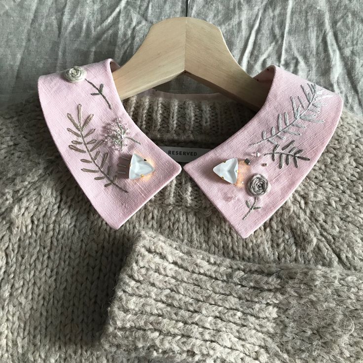 a close up of a sweater on a hanger with flowers and leaves painted on it