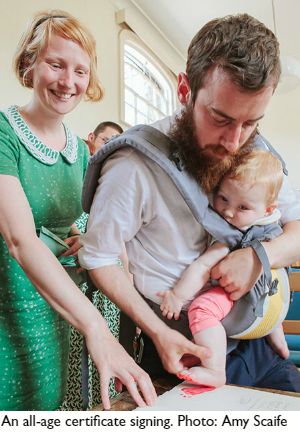 a man holding a baby in his arms while standing next to two women and one man