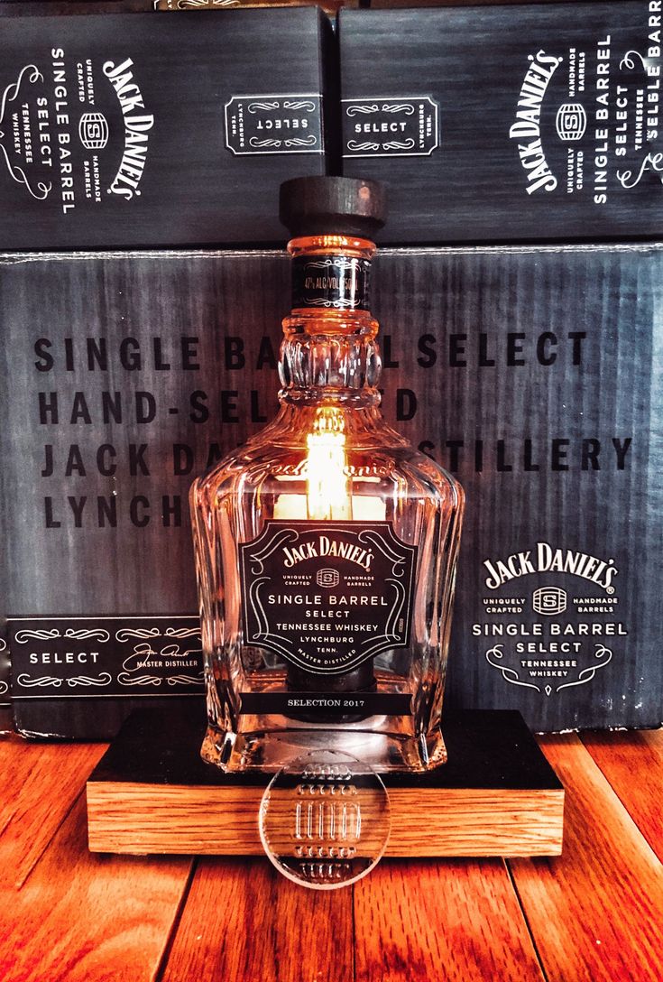 a bottle of jack daniels single barrel whiskey sitting on top of a wooden table next to two black boxes