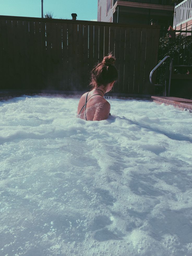 a woman sitting in the middle of a large hot tub filled with white foam and water