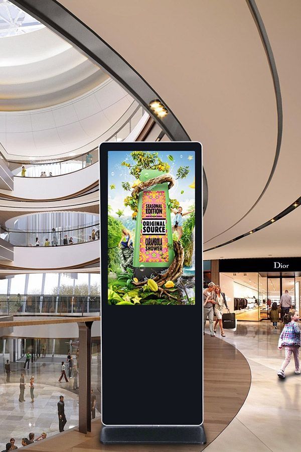 a digital sign in the middle of a mall with lots of people walking around it