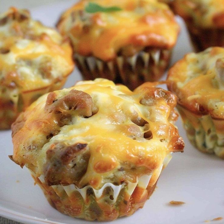 a white plate topped with muffins covered in cheese and sausage meat toppings