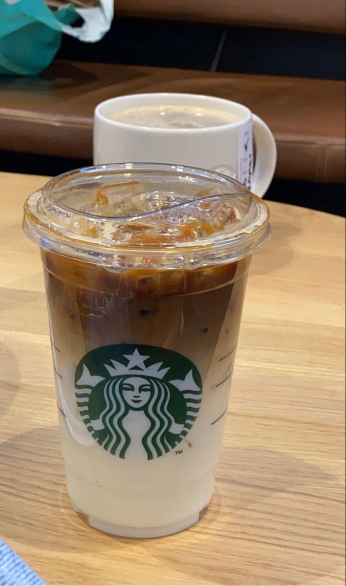 a cup of iced coffee sitting on top of a wooden table