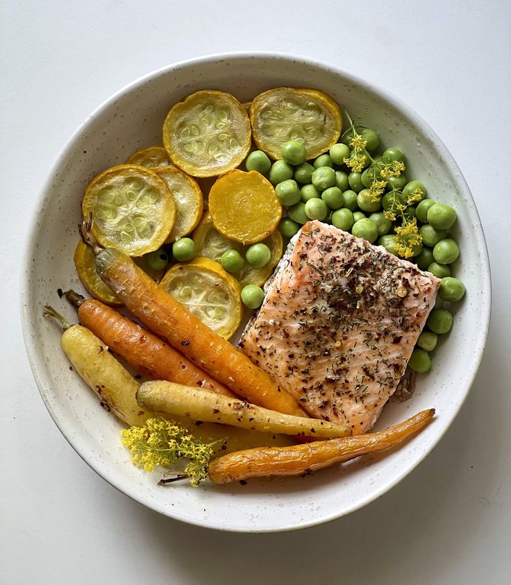 a white bowl filled with vegetables and fish