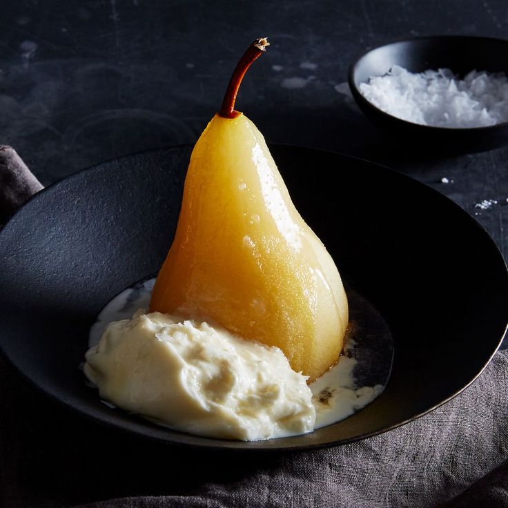 a black plate topped with mashed potatoes and a slice of pear sitting on top of it