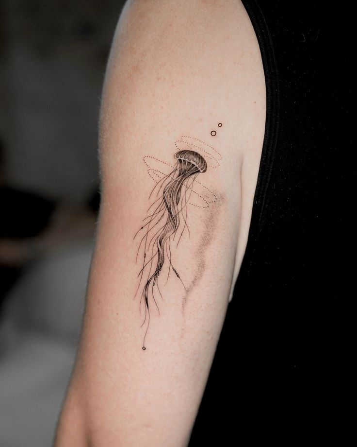 a woman's arm with a jellyfish tattoo on the left side of her arm