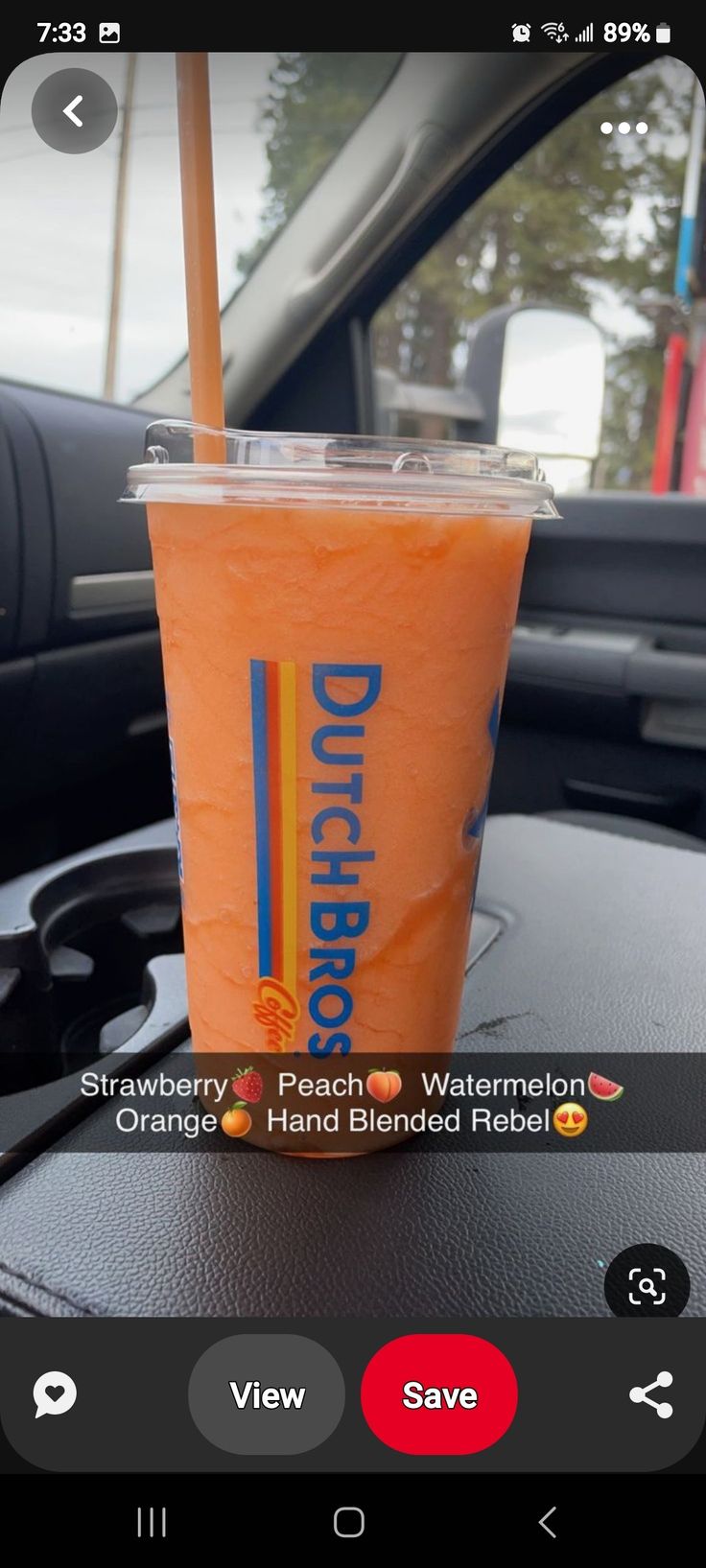 an orange drink sitting on top of a car dashboard