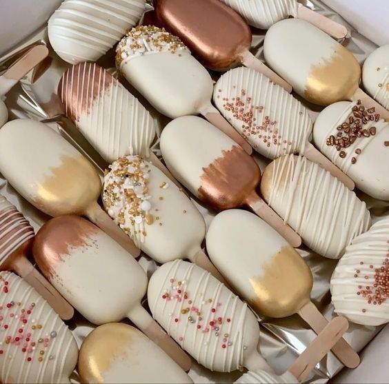 a box filled with lots of white and gold desserts