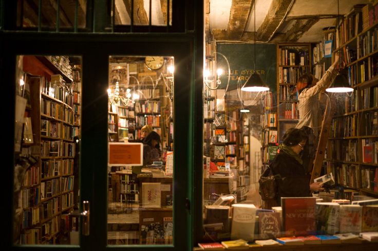 a man standing in front of a book store filled with books